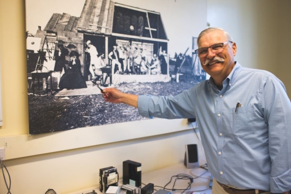 Terry Kovacs points to a print of Dartmouth's expedition to Burlington, Iowa in 1869